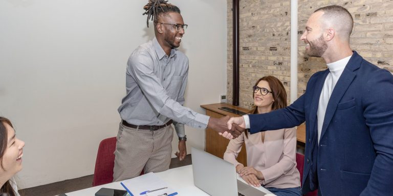 Multi-ethnic, modern young businessmen shaking hands and smiling while working in the creative office